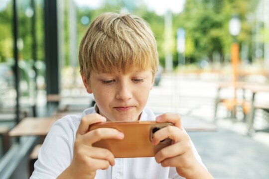 Preteen boy playing mobile video game on smartphone outdoors