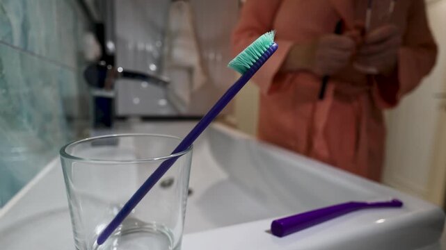 Woman opens new toothbrush packaging and swaps it with old on a bathroom counter