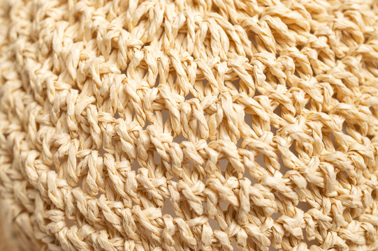Straw hat weave fills close-up frame, revealing dense natural fibers and circular handmade pattern. Textured surface suits craft education, material studies, fashion design, and organic branding.