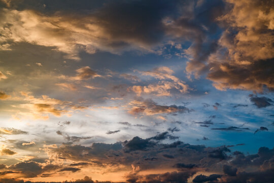 Golden hour light illuminates soft clouds as they move slowly across the vast evening sky providing a peaceful and serene view of nature at dusk