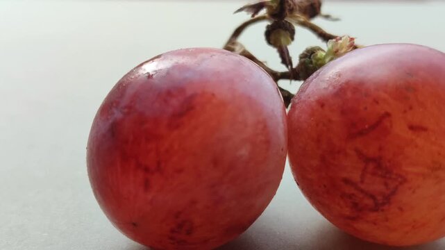 Fresh red grapes (Vitis vinifera) growing in a cluster, featuring smooth skin, rich red-purple color, and a natural appearance suitable for food and agricultural concepts.