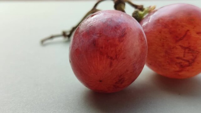 Fresh red grapes (Vitis vinifera) growing in a cluster, featuring smooth skin, rich red-purple color, and a natural appearance suitable for food and agricultural concepts.