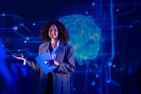 Woman gives a talk in front of a digital background with a brain design during a technology event