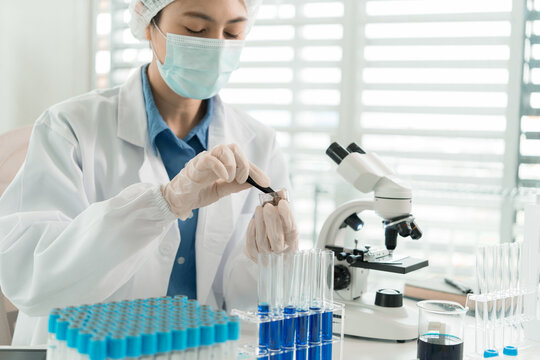Female Laboratory Scientist Analyzing Samples with Pipette, Microscope and Laptop in Modern Research Laboratory