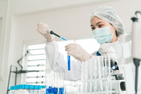 Female Laboratory Scientist Analyzing Samples with Pipette, Microscope and Laptop in Modern Research Laboratory