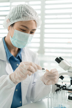 Female Laboratory Scientist Analyzing Samples with Pipette, Microscope and Laptop in Modern Research Laboratory