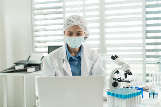 Female Laboratory Scientist Analyzing Samples with Pipette, Microscope and Laptop in Modern Research Laboratory