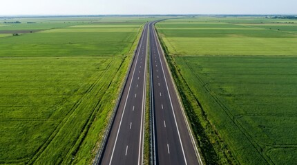 Obraz premium Aerial top view of a modern asphalt highway through lush green fields