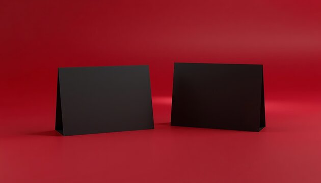Black folded table tent cards mockup on deep red background for branding.