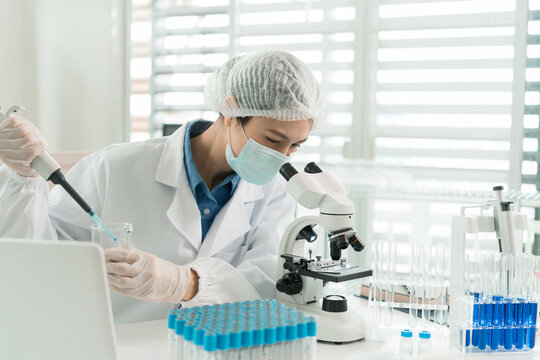 Female Laboratory Scientist Analyzing Samples with Pipette, Microscope and Laptop in Modern Research Laboratory