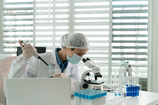 Female Laboratory Scientist Analyzing Samples with Pipette, Microscope and Laptop in Modern Research Laboratory