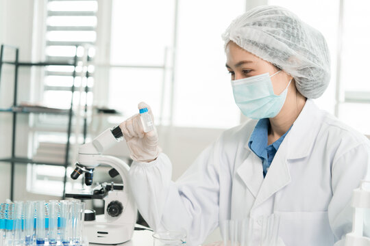 Female Laboratory Scientist Analyzing Samples with Pipette, Microscope and Laptop in Modern Research Laboratory
