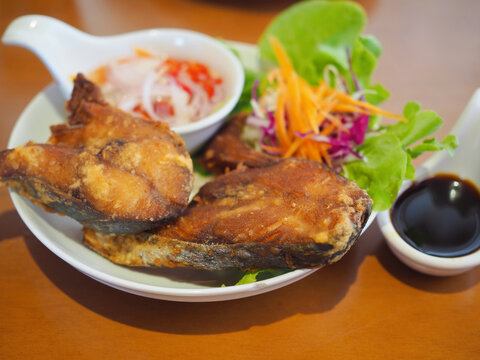 Sun-dried king mackerels is fried and served on a plate with dipping sauce in a bowl. It looks very appetizing and tastes delicious.