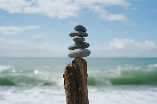 Balanced stack of smooth grey stones on a weathered wooden post