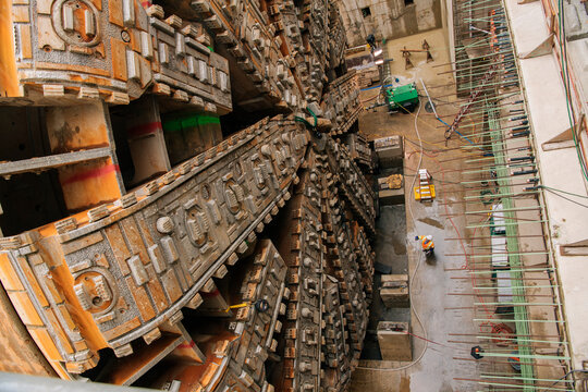 Two white workers observe tunnel boring machine drilling underground