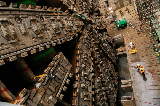 Construction white workers inspect a large tunnel boring machine