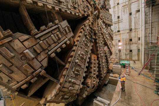 Two white workers inspect a huge tunnel boring machine