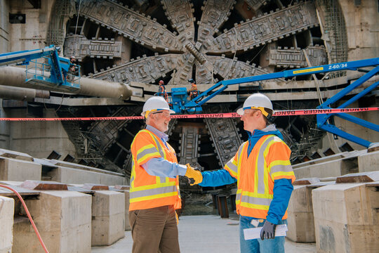Two construction white workers shake hands