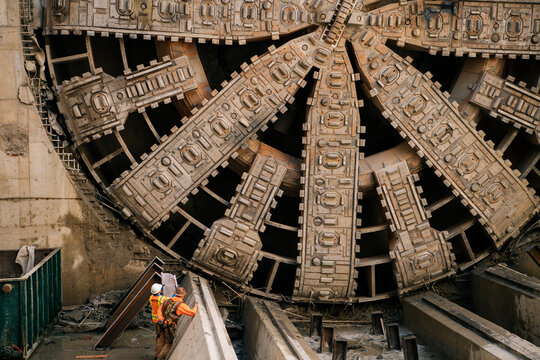 Construction white workers inspect plans by tunnel boring machine