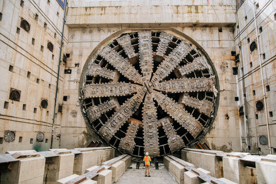 A construction white worker inspects a large tunnel boring machine