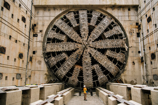 A white worker inspects a large tunnel boring machine
