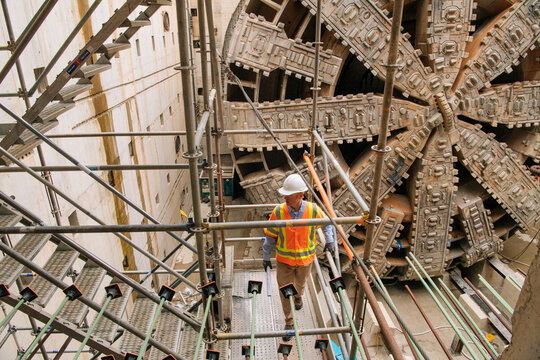 Two construction white workers inspecting a tunnel boring machine