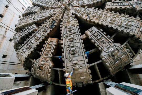 Construction white worker inspects tunnel boring machine drilling