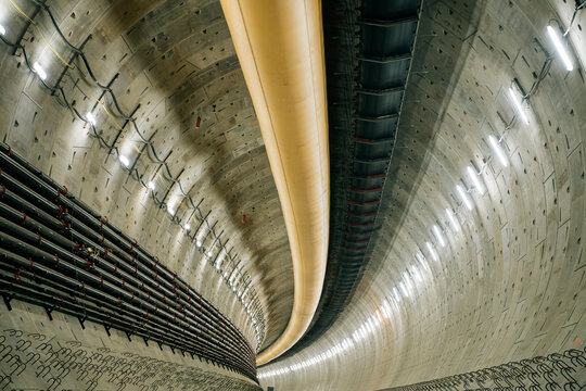 Interior of a large concrete tunnel with pipes and ventilation ducts