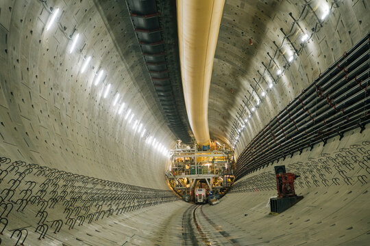 A large concrete tunnel with drilling equipment under construction