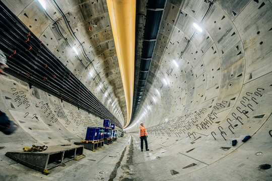A construction white worker inspects a large underground tunnel