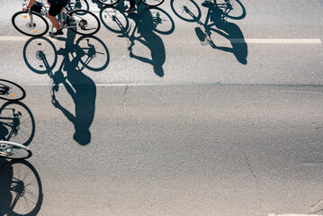 Obraz premium Aerial View of Cyclists Riding on Asphalt Street with Long Shadows