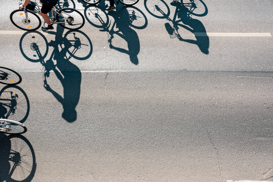 Aerial View of Cyclists Riding on Asphalt Street with Long Shadows