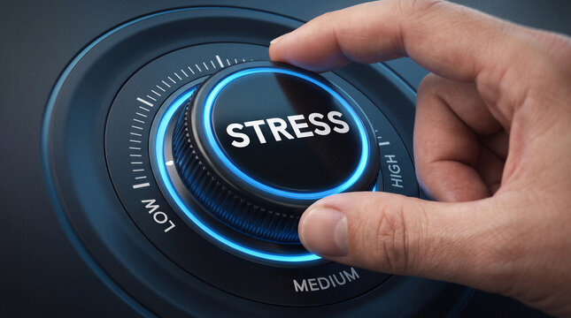 Close up of a hand turning an illuminated stress control dial from low toward higher levels, conceptual image of pressure management, anxiety, burnout and emotional regulation.
