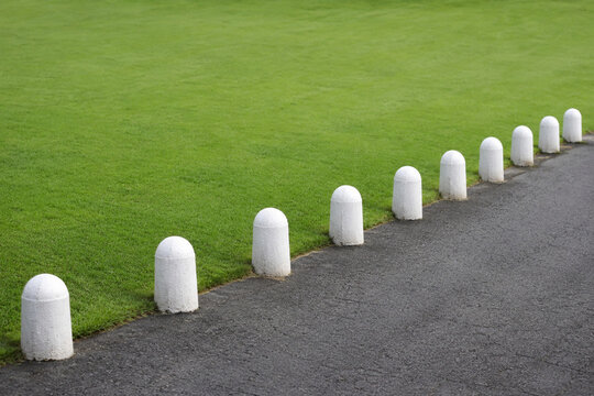 Row of white stone bollards and manicured lawn, boundary and landscaping concept
