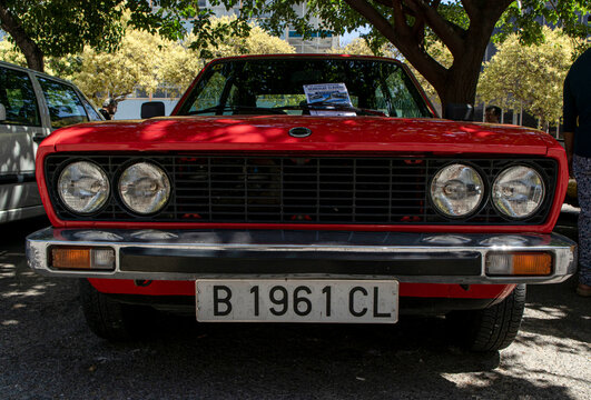 Tavernes Blanques, Spain - June 14, 2026.Classic red SEAT sedan with quad round headlights and black front grille parked under trees in Spain