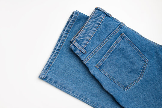 Blue indigo jeans on white background, top view with space for text. Fashionable jeans made of natural cotton, wardrobe item. Fashion and style concept, shopping
