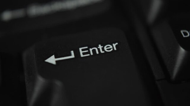 Macro close-up video of the Enter key on a black computer keyboard. Technology, business, and data input concept with shallow depth of field.
