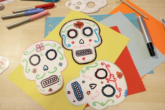 Colorful handmade calavera masks with craft supplies for Day of the Dead