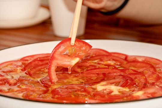 chopsticks picking homemade cold tomato salad from plate