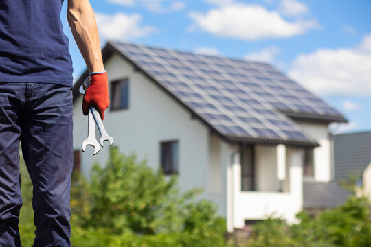 Solar Panel Installer. Solar Worker holding Tools on  Solar Panels Rooftop Backgound.