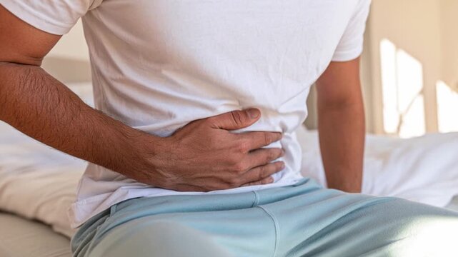 A man just woke up sitting in bed, suffering from severe upper abdominal pain and symptoms of gastritis