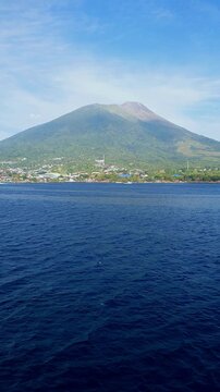A view of Mount Gamalama captured from aboard a boat, showing the volcanic mountain and surrounding waters of Ternate Island, North Maluku.