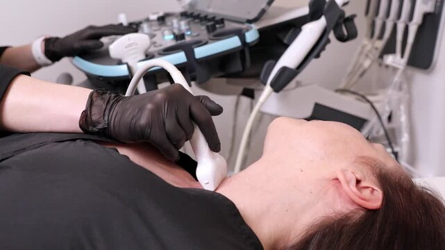 Close up hand of female sonographer doctor does an ultrasound of the thyroid gland, examines the patient's throat, nodes, applies a medical ultrasound sensor to the neck of a woman lying on a couch.
