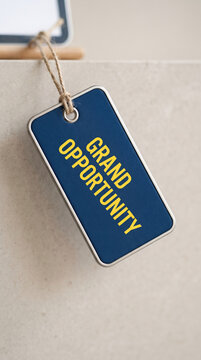 A blue tag with yellow text reading "GRAND OPPORTUNITY", symbolizing a business chance or a significant event, set against a neutral background