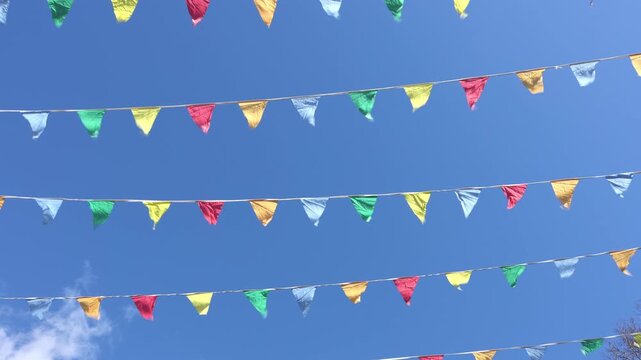 Colorful triangular flags fluttering in wind against clear blue sky