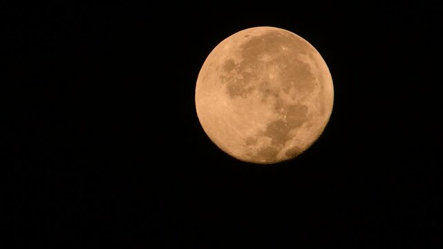 A full moon moving at an accelerated pace across the night sky