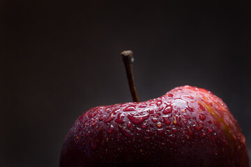 Close-up of fresh red apple covered in water droplets on dark background © Pure Asset