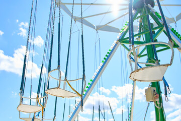 Empty swing carousel seats hanging from chains against blue sky © barmaleeva