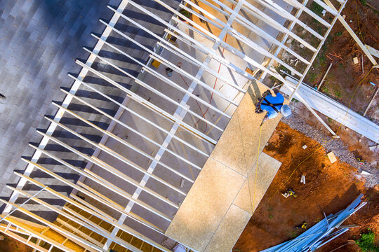 Several workers are assembling beams framework for building at site in an outdoor work area