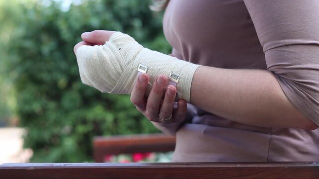 Fixation of the wrist with an elastic bandage after a sports injury or fall. A person holds an injured hand with a medical bandage applied. Concept of first aid, treatment of injuries. Injured hand